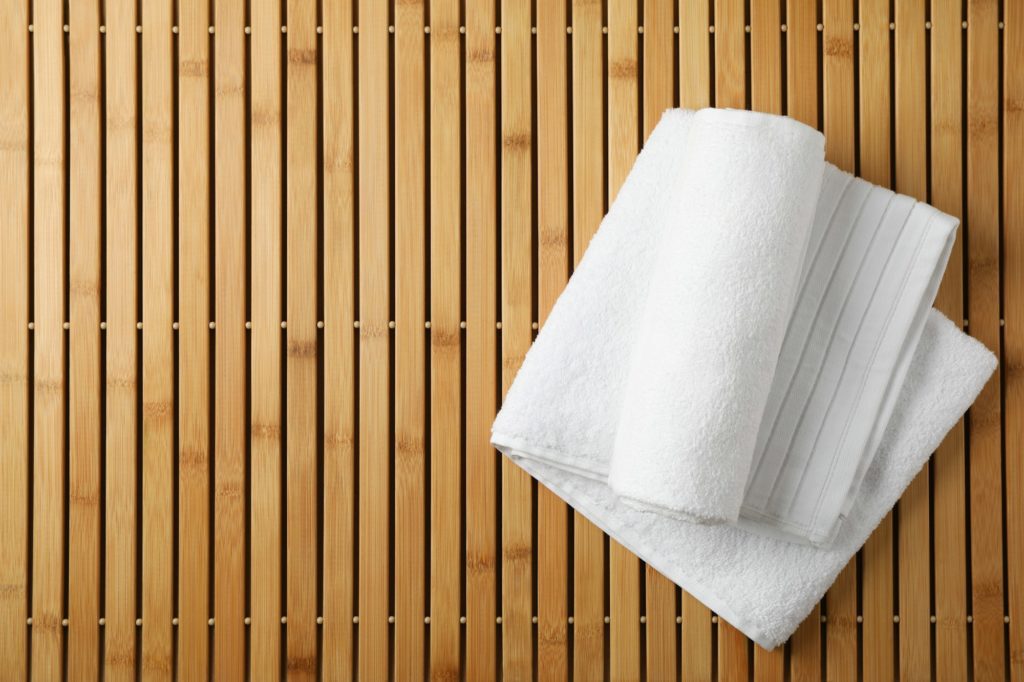 Blog 5 White fresh towels on bamboo background, top view
