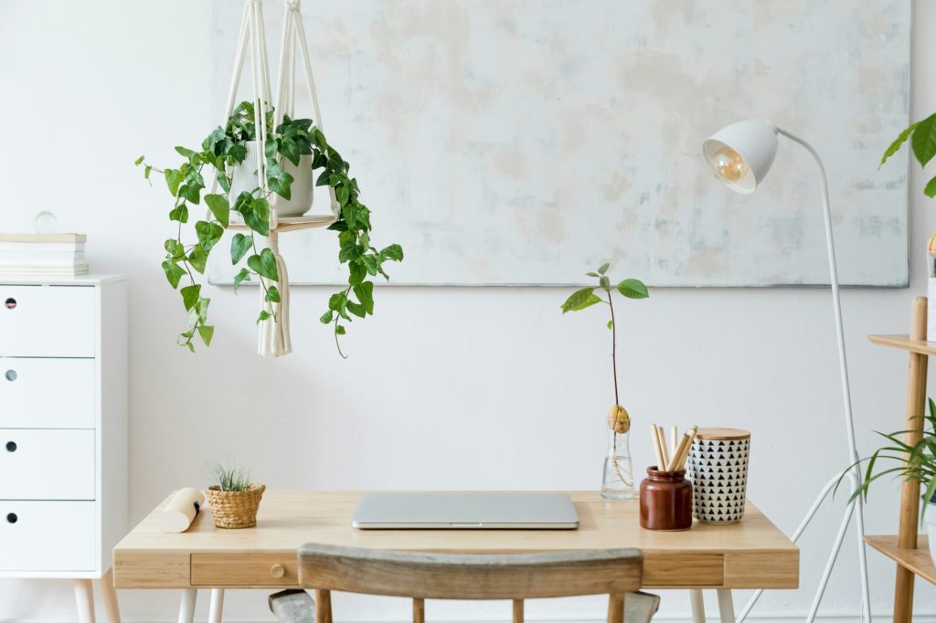 Stylish and boho home interior of open space with wooden desk.