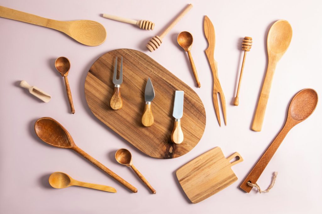 various wooden and bamboo kitchen utensils are laid out on a pastel background. top view. flat lay.